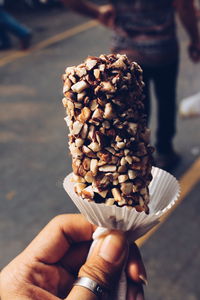Cropped image of woman holding ice cream candy on city street