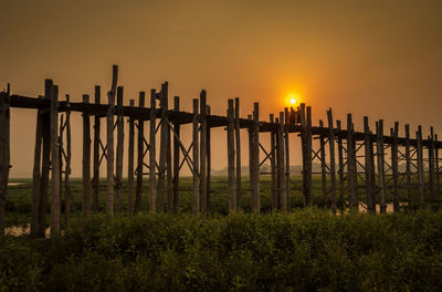 Wooden fence on field against sky during sunset