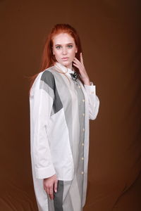 Portrait of young woman standing against gray background