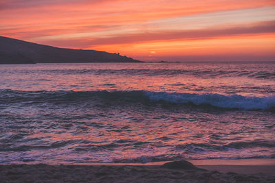 Scenic view of sea against dramatic sky during sunset