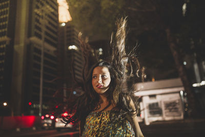 Portrait of woman standing in illuminated city at night