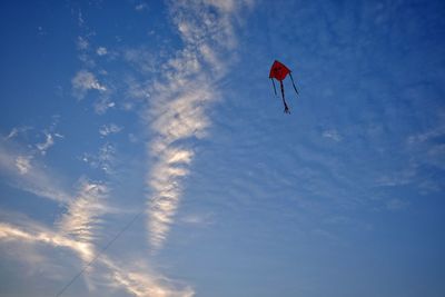 Low angle view of person paragliding against blue sky