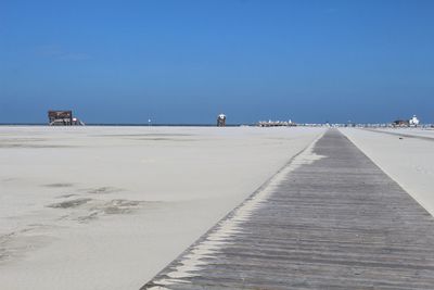 Surface level of empty beach against clear blue sky