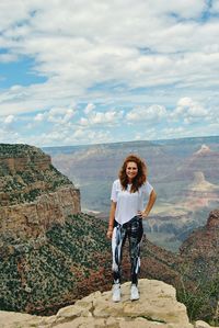 Portrait of woman standing on rock against sky