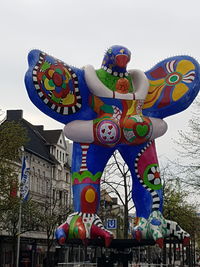 Low angle view of balloons against building against sky