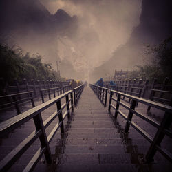 Footbridge amidst trees against sky