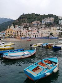 Boats moored on beach against buildings in city