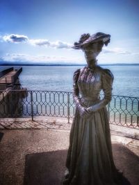 Rear view of woman standing by sea against sky