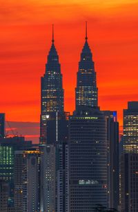 Illuminated buildings against orange sky