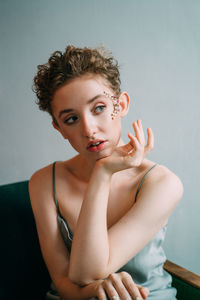 Portrait of young woman sitting against wall