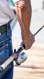 Midsection of man holding fishing rod