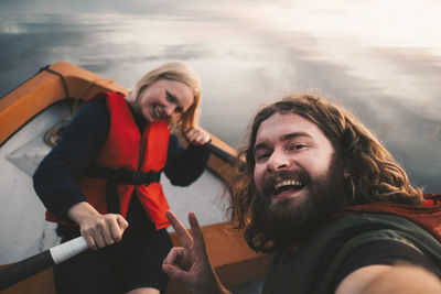 Portrait of happy couple sitting in boat on lake