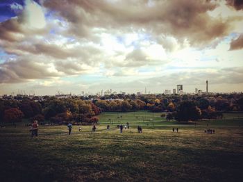 People on soccer field against cloudy sky