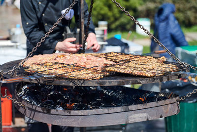 Cropped hand of man preparing food on barbecue grill