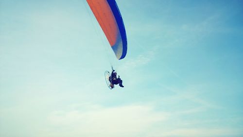 Low angle view of man paragliding against sky