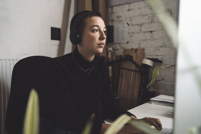 Businesswoman with headphones working on computer at workplace