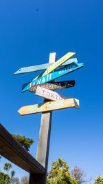 Low angle view of sign board against blue sky