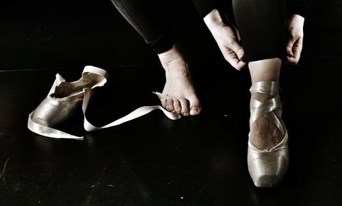 Low section of female ballet dancer wearing shoes on floor