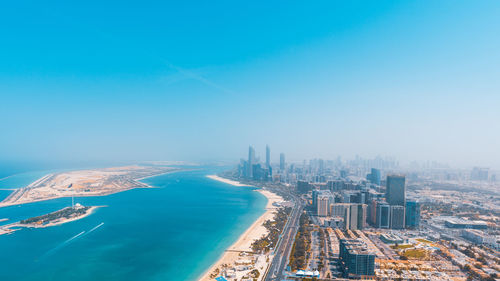 High angle view of buildings by sea against blue sky