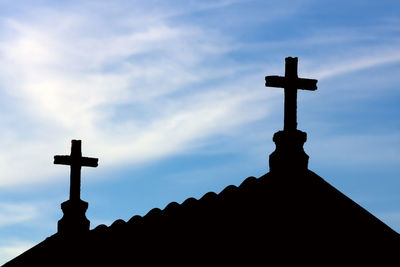 Low angle view of cross in cemetery against sky