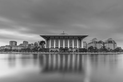 Reflection of building in lake against cloudy sky