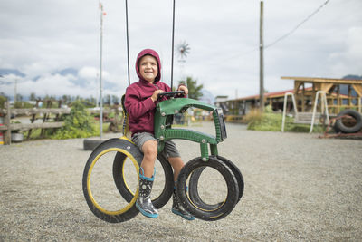 Happy boy sits on play ride on tractor made from recycled tires