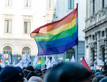 Rainbow flag in crowd against buildings