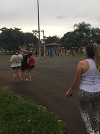 Rear view of people walking on street against sky