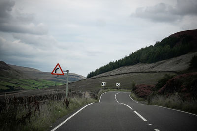 Empty road amidst mountains against sky