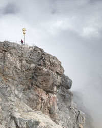 Low angle view of man standing on cliff against sky