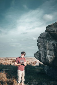 Full length of boy standing on rock against sky