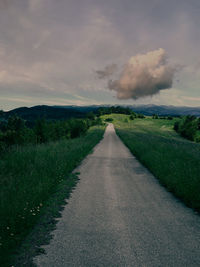Road amidst field against sky