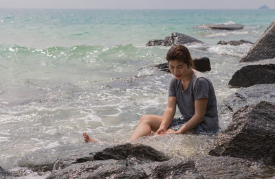 Woman sitting in sea on shore at beach