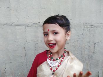 Portrait of smiling girl wearing sari while standing against wall