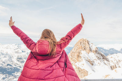 Rear view of woman walking on snowcapped mountain against sky