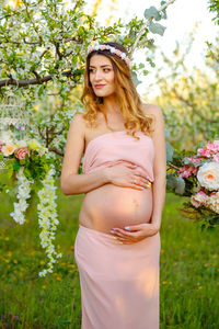 Portrait of beautiful young woman standing by flowering plants