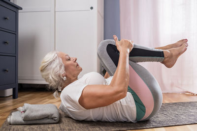 Side view of woman using mobile phone while sitting on sofa at home