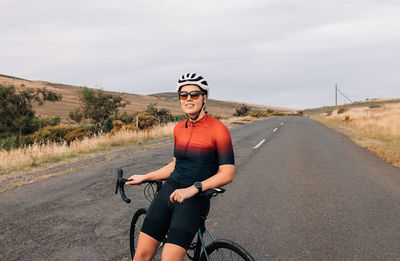 Man leaning on bicycle on road