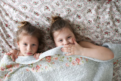 Sister's girls play and cuddle under a blanket, emotions. concept childhood and related 