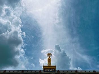 Low angle view of buddha statue standing against sky