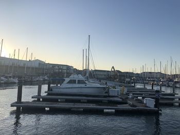 Sailboats moored in harbor at sunset