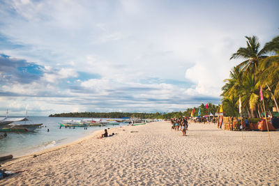 Scenic view of people enjoying at beach during sunset