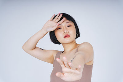 Portrait of young woman gesturing against white background