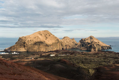 Scenic view of rocky shore and sea against sky