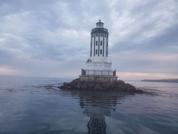 Lighthouse by sea against sky