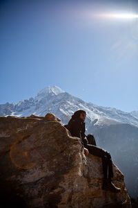 Man standing on rock by mountain against sky