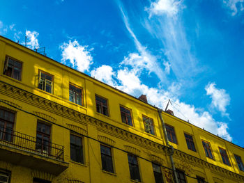 Low angle view of yellow building against blue sky