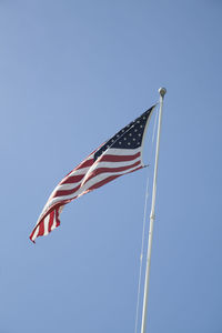 Low angle view of flags against clear blue sky