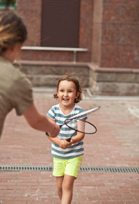 Mother playing tennis with daughter outdoors