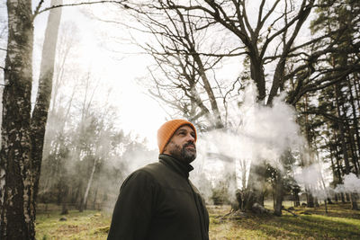 Mature male hiker exploring forest in foggy weather